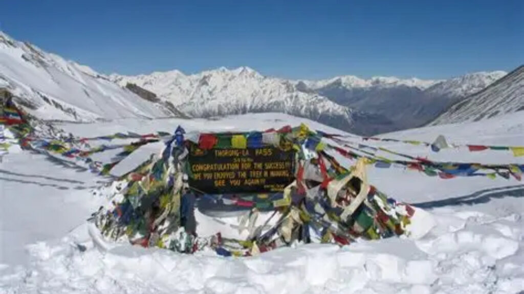 Thorong La Pass covered in snow with prayer flags